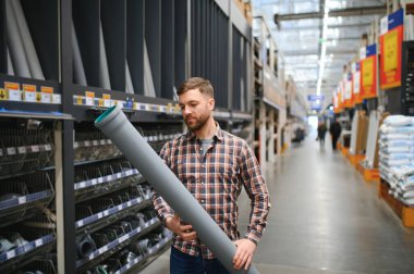 male plumber in a hardware store chooses the sewer pipes, the concept of plumbing work in the house.