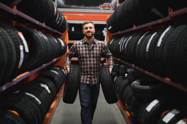 Mutlu erkek müşteri süpermarkette satın almak için yeni lastikler alarak. Mutlu görünüyor. Araba mal ile büyük alışveriş merkezi.