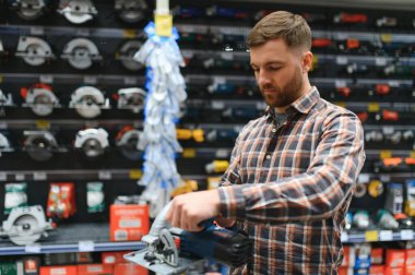 Hırdavatçıdaki bir adam yeni bir yörünge zımpara makinesi seçer..