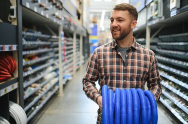 male plumber in a hardware store chooses the sewer pipes, the concept of plumbing work in the house.