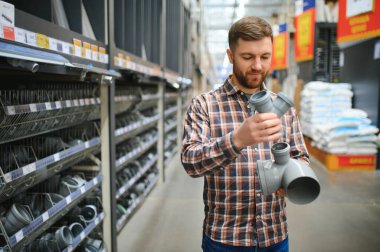 Su tesisatçısı vitrininin yanında duran lağım borularını seçen yakışıklı adam..