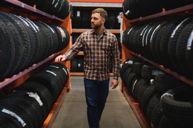 Adam araba tamirhanesinde kış lastiklerini seçiyor..