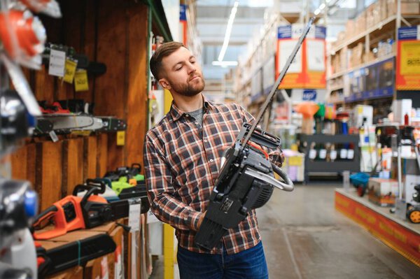Рабочие держит электропилу в магазине инструментов.