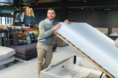 Mağazadaki ortopedik yatağı seçen adam.