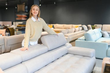 Mobilya dükkanında kanepe test eden neşeli genç bir kadının portresi..