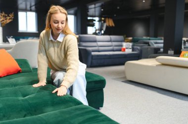 Mobilya dükkanında kanepe test eden neşeli genç bir kadının portresi..