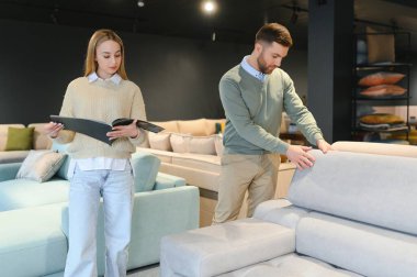 Evli çift mobilya mağazasındaki en iyi yeni kanepeyi seçiyor..