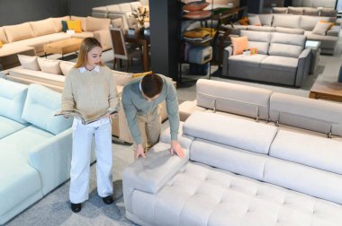 Evli çift mobilya mağazasındaki en iyi yeni kanepeyi seçiyor..