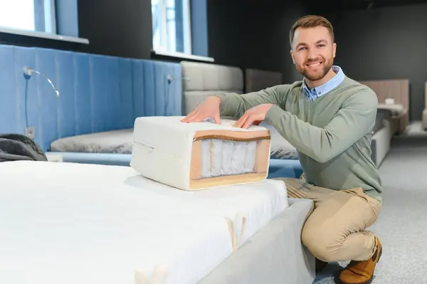 Man choosing orthopedic mattress in store.
