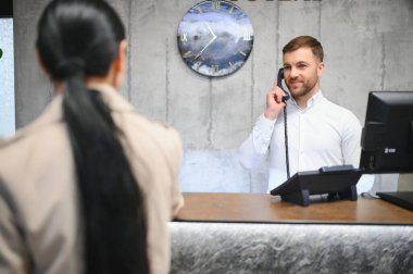 Otel lobisinde beyaz gömlek giyen genç bir resepsiyonistin portresi..