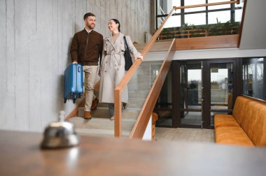 Otele giren mutlu çift bavullarını çekerek, tatil konsepti.