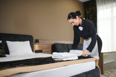 Hizmetçi otel odasında çiçekli temiz havlular tutuyor..