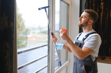 Ofisin camlarını temizleyen genç adam..