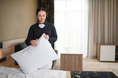 Genç otel hizmetçisi yatağı yapıyor..