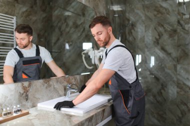 Bir adam banyoda kabine üzerinde lavabo ayarlama.