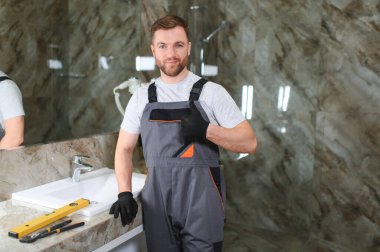 Bir adam banyoda kabine üzerinde lavabo ayarlama.