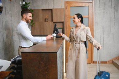 Female guests come with bags and suitcases to the hotel reception in the lobby.