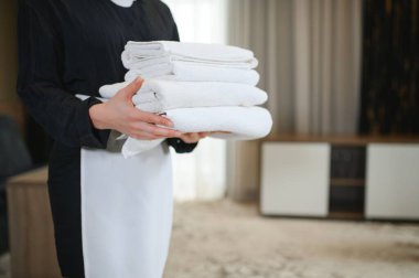 Otel odasında, closeup taze havlu ile çiçek tutan hizmetçi.