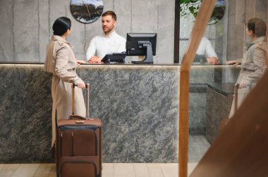 Female guests come with bags and suitcases to the hotel reception in the lobby.
