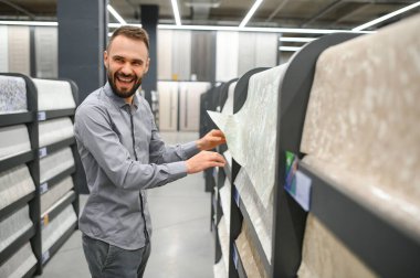 Hırdavatçıda duvar kağıtlarını seçen erkek müteahhit.