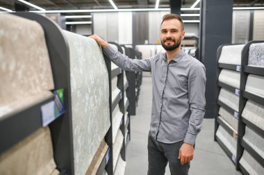 Hırdavatçıda duvar kağıtlarını seçen erkek müteahhit.