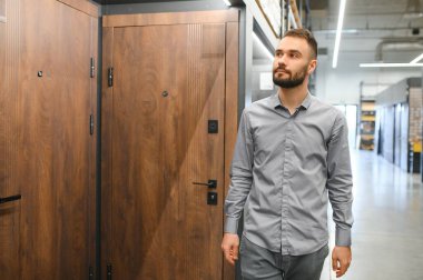 Genç bir adam hırdavatçıdaki metal ön kapıyı seçiyor..