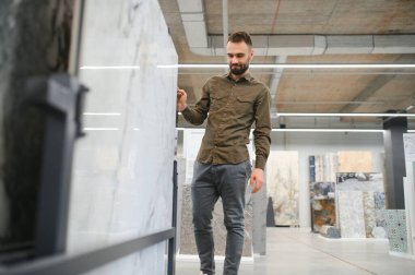 İnşaat malzemeleri mağazasında seramik fayans seçen yakışıklı bir adam..