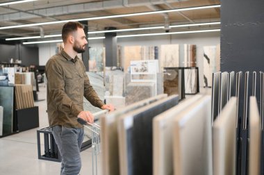 Hırdavatçıdaki banyo için duvar taşı malzemesi seçen kendinden emin bir erkek müşteri..