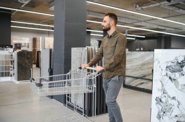 Hırdavatçıdaki banyo için duvar taşı malzemesi seçen kendinden emin bir erkek müşteri..