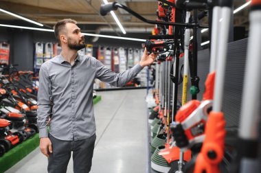 Bahçe gereçleri dükkanında elektrikli çim biçme makinesi olan bir müşteri..