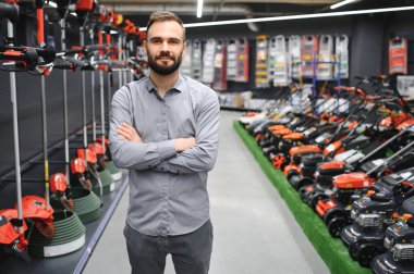 Bahçe gereçleri dükkanında elektrikli çim biçme makinesi olan bir müşteri..