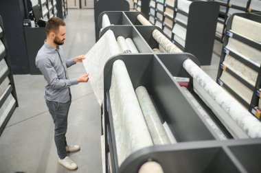 Hırdavatçıda duvar kağıtlarını seçen erkek müteahhit.