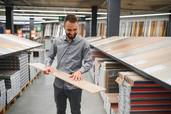 Продавец-консультант в хозяйственном магазине продает ламинат..