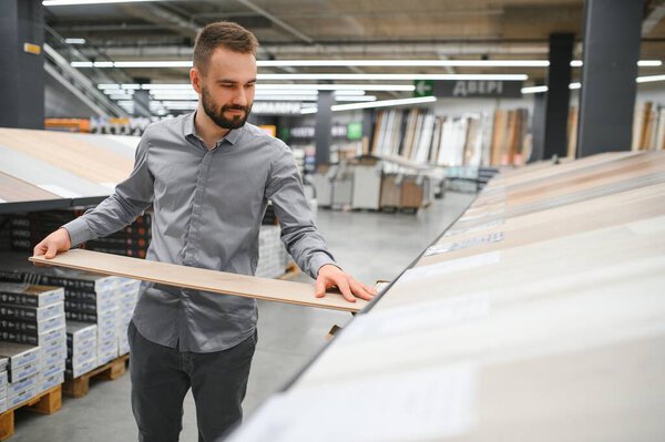 Мужчина выбирает пол в магазине бытовой техники.