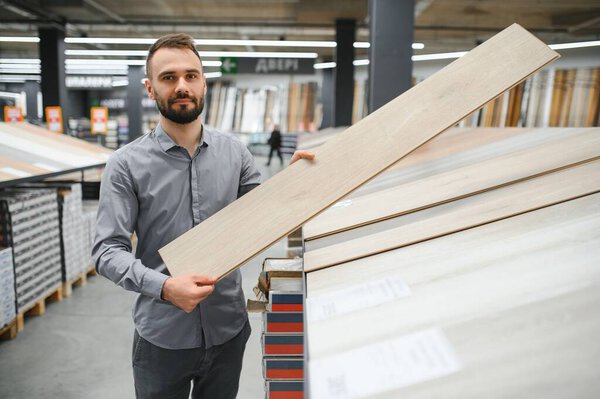 Мужчина выбирает пол в магазине бытовой техники.