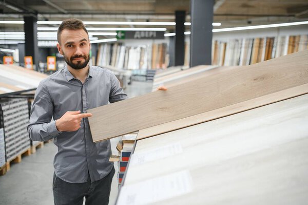 Мужчина выбирает пол в магазине бытовой техники.