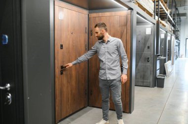 Genç bir adam hırdavatçıdaki metal ön kapıyı seçiyor..