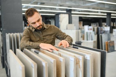 Hırdavatçıdaki banyo için duvar taşı malzemesi seçen kendinden emin bir erkek müşteri..