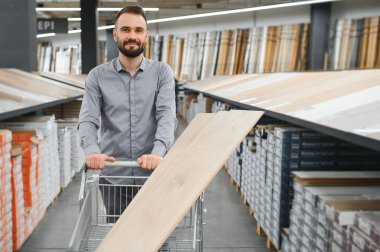 Genç bir adam Laminat parke donanım deposunda seçer..
