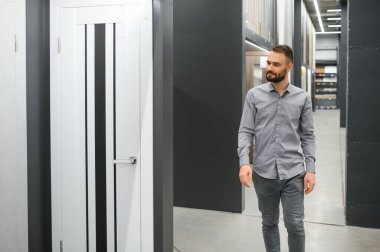 Bir erkek ev için bir kapı seçer. Hırdavatçıdan kapı almak..