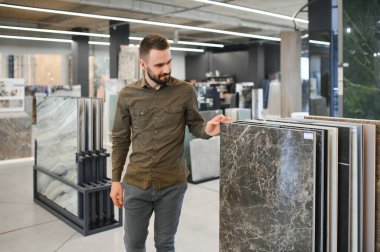 Hırdavatçıdaki banyo için duvar taşı malzemesi seçen kendinden emin bir erkek müşteri..