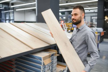 Genç bir adam Laminat parke donanım deposunda seçer..