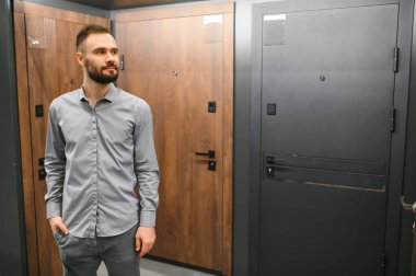 Genç bir adam hırdavatçıdaki metal ön kapıyı seçiyor..