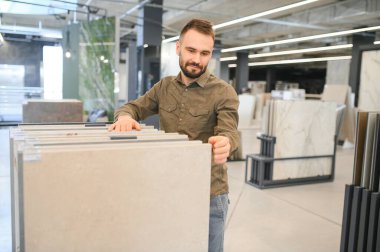 İnşaat malzemeleri mağazasında seramik fayans seçen yakışıklı bir adam..