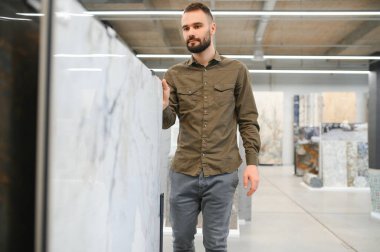 Hırdavatçıdaki banyo için duvar taşı malzemesi seçen kendinden emin bir erkek müşteri..