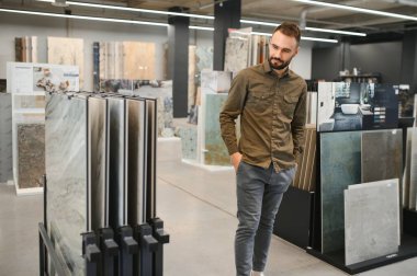 Alıcı bir inşaat dükkanındaki seramik fayansları inceliyor.