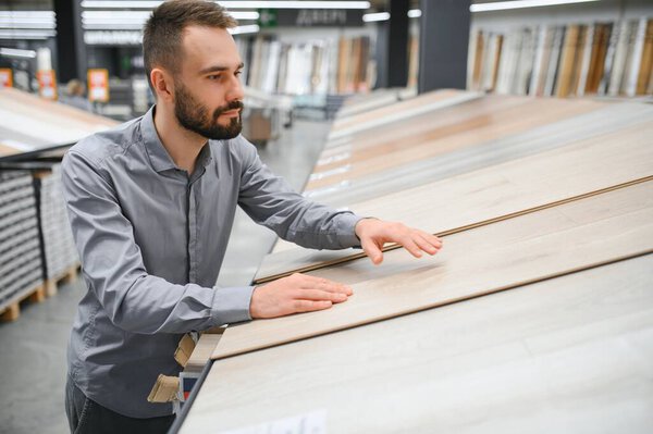 Мужчина выбирает пол в магазине бытовой техники.