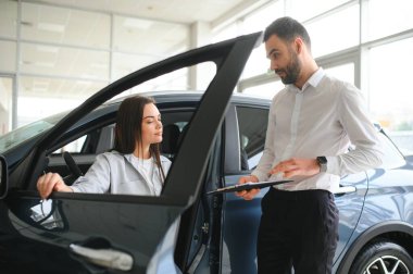 Yeni erkek mağaza asistanının direksiyonunda oturan mutlu, beyaz kadın müşteri kadın müşteri seçmesine yardım ediyor..