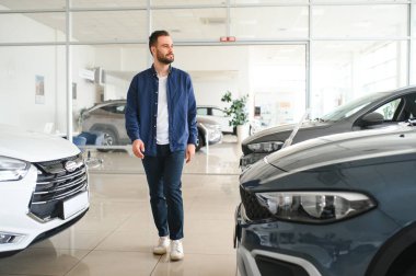 Genç adam yeni bir araç içinde araba Bayilik seçmektir.