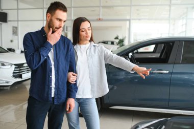 Galeriye başarılı bir ziyaret. Mutlu genç çift aile için yeni bir araba seçer ve alır..